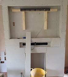 tv mounting in progress, light grey plaster board, wooden beams in place
